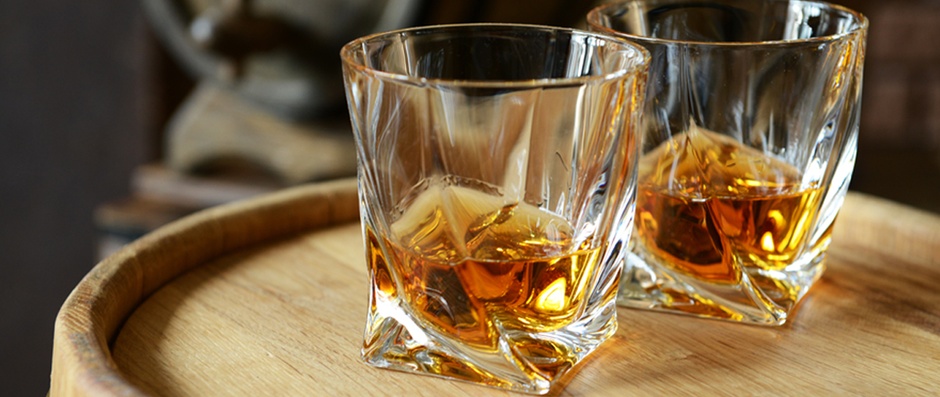 Glasses of brandy in cellar with old barrels